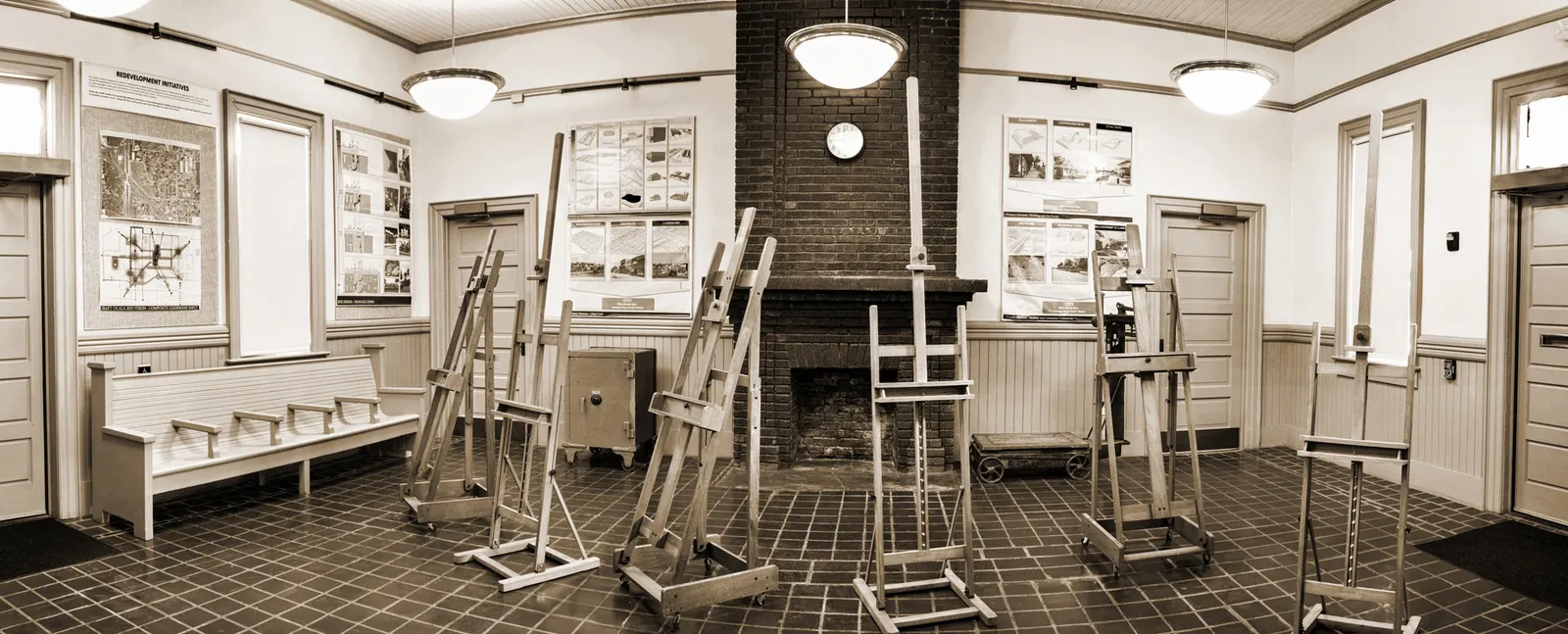 A restored salon with easels, a station bench and a brick fireplace